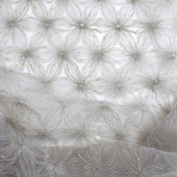 EOS Fabrics shimmering snowflake tulle in smoke gray with metallic gold accents and textured mesh applique detail.