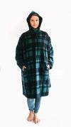 Photo of young woman wearing parka with hood pulled up.  hands are in both pockets and she looks forward towards the camera.