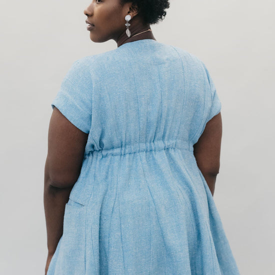 Back view of young African American woman with head looking over her shoulder wearing the women's Ghanaian Smock.