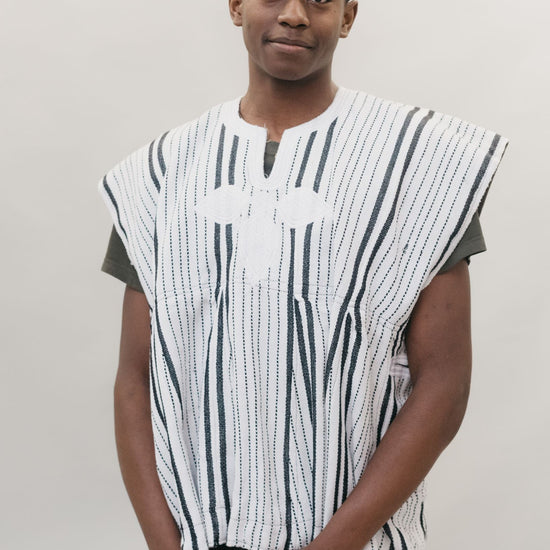 Front view of young African American man standing in front of a white studio backdrop wearing the men's Ghanaian Smock