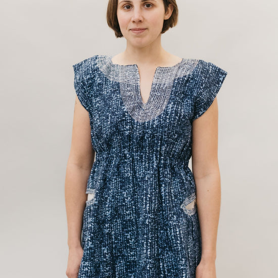 young brunette white woman standing in front of a white studio backdrop wearing the Ghanaian Smock.