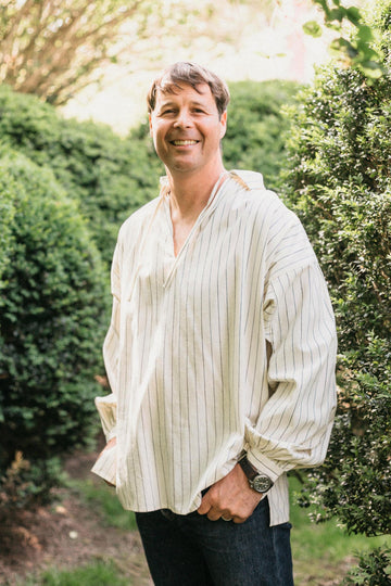 Smiling man, standing with hands in pockets,surrounded by greenery, wearing 204 Missouri River Boatman's Shirt
