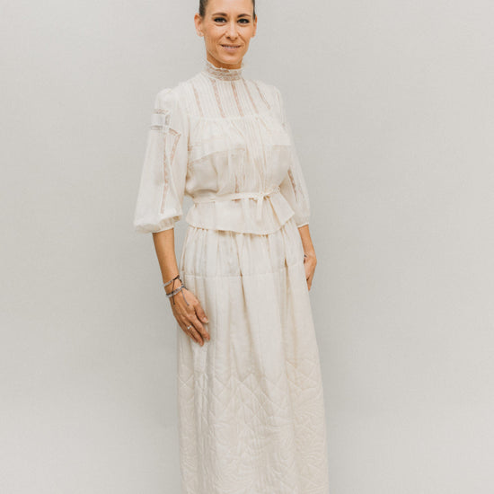 Blonde woman standing in front of white studio backdrop wearing 206 Gibson Girl Blouse with matching skirt.