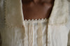 Close up of 210 Armistice Blouse long collar forming a deep rectangle, trimmed with lace at the edges of the collar worn by African woman