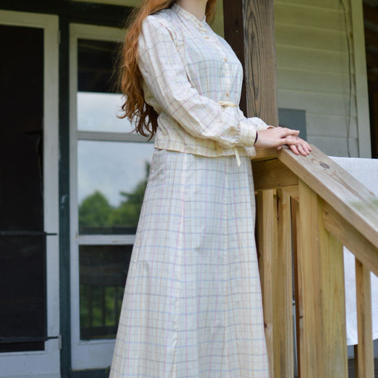 Young red head woman standing on a porch wearing 216 Schoolmistresses Shirtwaist and Skirt.