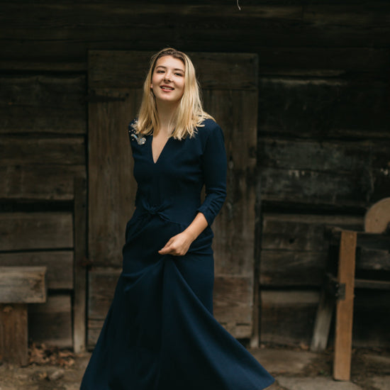 young blonde woman about standing in front of a small wooden building twirling the skirt if the 233 Glamour Girl Dress