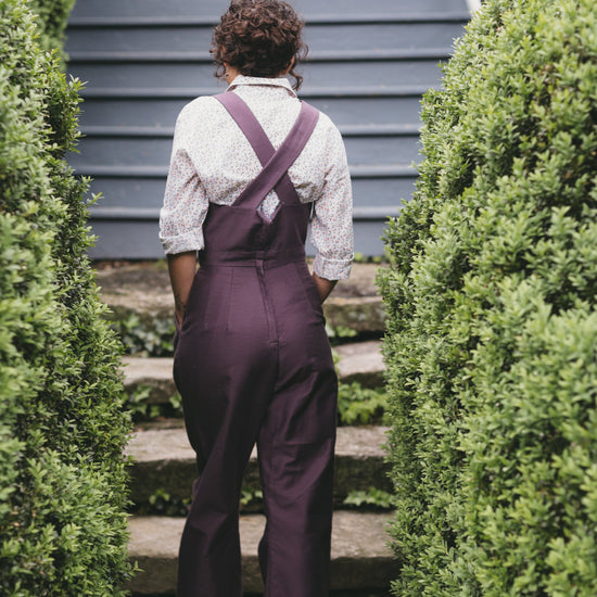 Back view of young woman walking wearing the 240 Rosie the Riveter Overalls.
