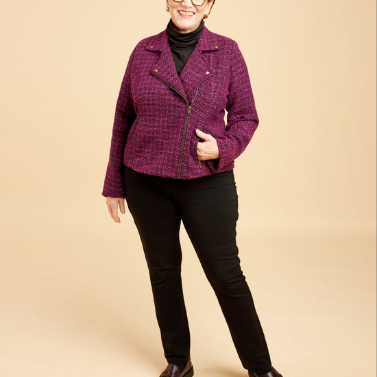 Woman wearing a purple jacket and black pants on a beige background. This biker jacket is the Canton Moto Jacket sewing pattern from Cashmerette.