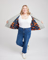 Woman wearing a white top, blue jeans, and a colorful jacket over her shoulders on a plain background. This biker jacket is the Canton Moto Jacket sewing pattern from Cashmerette.