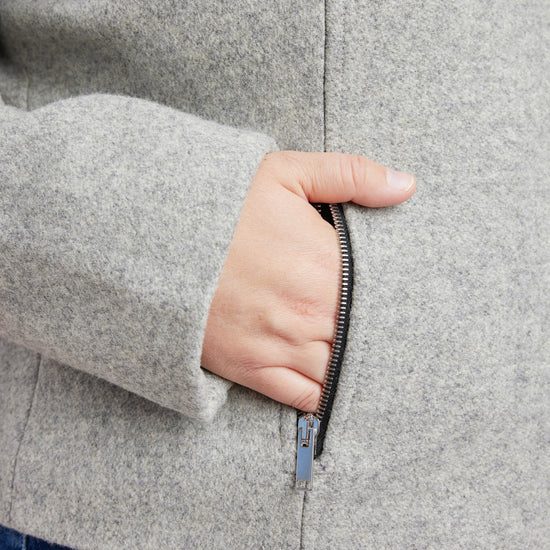 Person wearing a gray coat with a hand reaching into the pocket. This biker jacket is the Canton Moto Jacket sewing pattern from Cashmerette.
