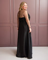 Woman wearing a black evening gown with sheer sleeves against a pink paneled wall. This is the Ellington Dress sewing pattern from Cashmerette.