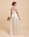 Woman in a white off-shoulder wedding dress holding a bouquet on a beige background. This dress is the Ellington Strapless Dress sewing pattern from Cashmerette.