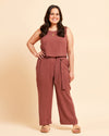 Woman wearing a brown top and brown pants in front of a yellow background. These shorts are the Everett Pants & Shorts sewing pattern from Cashmerette.