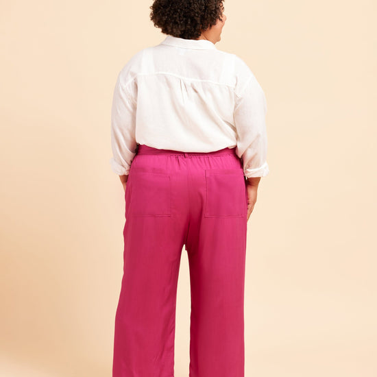 Person wearing a white shirt and pink pants on a beige background. These pants are the Everett Pants & Shorts sewing pattern from Cashmerette.