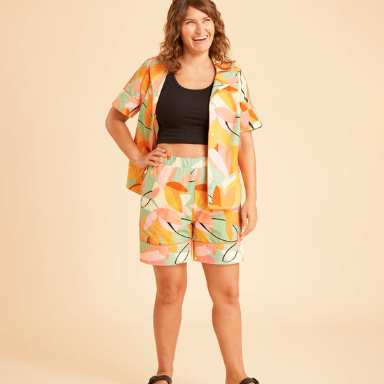 Woman wearing a colorful outfit with a patterned jacket and shorts on a beige background. This is the Fiske Sleepwear Set sewing pattern from Cashmerette.
