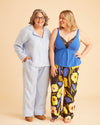 Two women standing side by side against a beige background, one in light blue outfit and the other in colorful floral pants. This is the Fiske Sleepwear Set sewing pattern from Cashmerette.