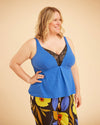 Woman wearing a blue top with floral pants on a beige background. This is the Fiske Sleepwear Set sewing pattern from Cashmerette.