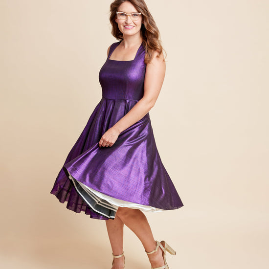 Woman wearing a purple dress on a beige background. This is the Grafton Dress, Top & Skirt sewing pattern from Cashmrette.