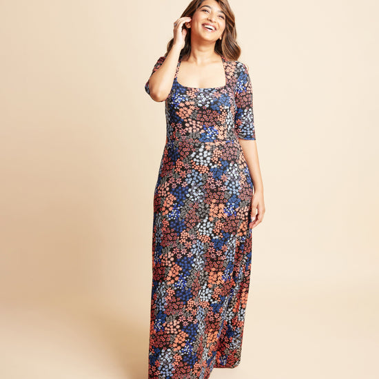 Woman wearing a floral dress on a beige background. This is the Grafton Dress, Top & Skirt sewing pattern from Cashmrette.
