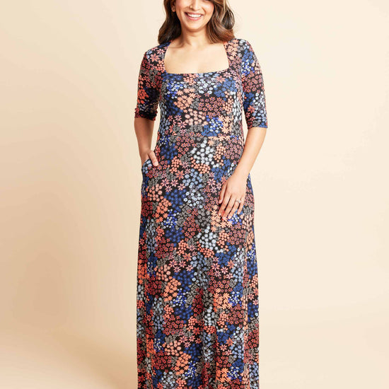 Woman wearing a floral dress on a beige background. This is the Grafton Dress, Top & Skirt sewing pattern from Cashmrette.