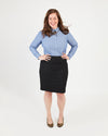 Woman wearing a light blue shirt and black skirt on a white background. This button-up shirt is the Harrison Shirt sewing pattern from Cashmerette.