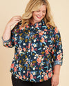 Woman wearing a floral blouse on a beige background. This button-up shirt is the Harrison Shirt sewing pattern from Cashmerette.
