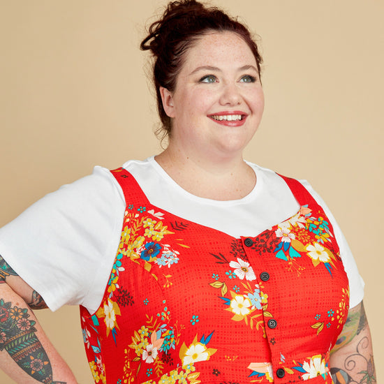 Woman wearing a red floral dress over a white shirt against a beige background. This is the Holyoke Maxi Dress & Skirt sewing pattern from Cashmerette.