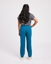 Person wearing blue pants and a striped shirt on a white background. These pants are the Meriam Trousers sewing pattern from Cashmerette.
