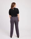 Woman wearing a black blouse and patterned pants on a white background. These pants are the Meriam Trousers sewing pattern from Cashmerette.