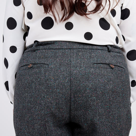 Person wearing a polka dot blouse and gray pants on a white background. These pants are the Meriam Trousers sewing pattern from Cashmerette.