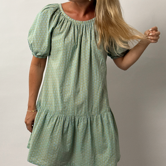 Woman wearing a green dress against a plain background