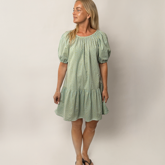 Woman wearing a green dress with puff sleeves against a plain background
