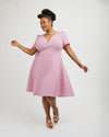 Woman wearing a pink dress on a white background. This dress is the Roseclair Wrap Dress sewing pattern from Cashmerette.