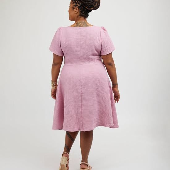 Woman wearing a pink dress on a white background. This dress is the Roseclair Wrap Dress sewing pattern from Cashmerette.