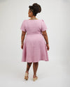 Woman wearing a pink dress on a white background. This dress is the Roseclair Wrap Dress sewing pattern from Cashmerette.