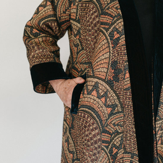 Close up of Turkish coat with view of side pocket.  Model has hand partially in pocket.