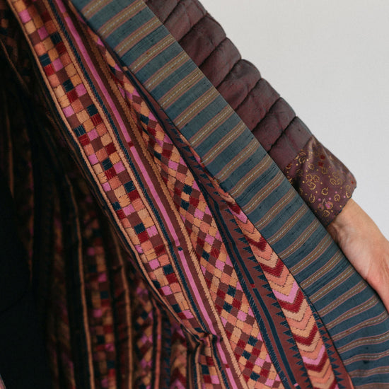 Close up of inner contrasting fabric and overlapping band on front opening and cuff.  Model is holding the jacket open to show detail.