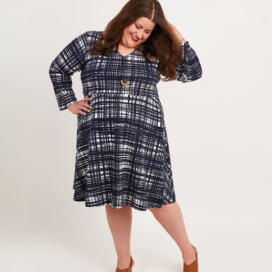 Woman wearing a blue plaid dress on a white background. This dress is the Turner Dress sewing pattern from Cashmerette.