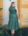 Woman wearing a blue and gold patterned dress standing in front of a stone building.. This dress is the Upton Dress & Skirt sewing pattern from Cashmerette.