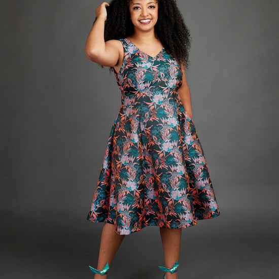 Woman wearing a floral dress against a gray background. This dress is the Upton Dress & Skirt sewing pattern from Cashmerette.
