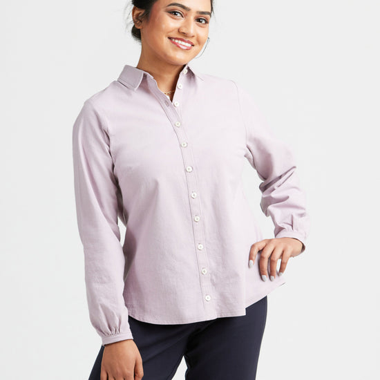 Woman wearing a light purple button-up shirt and dark pants on a white background. This top is the Vernon Shirt sewing pattern from Cashmerette.