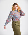 Woman wearing a patterned blouse and green pants on a white background. This top is the Vernon Shirt sewing pattern from Cashmerette.