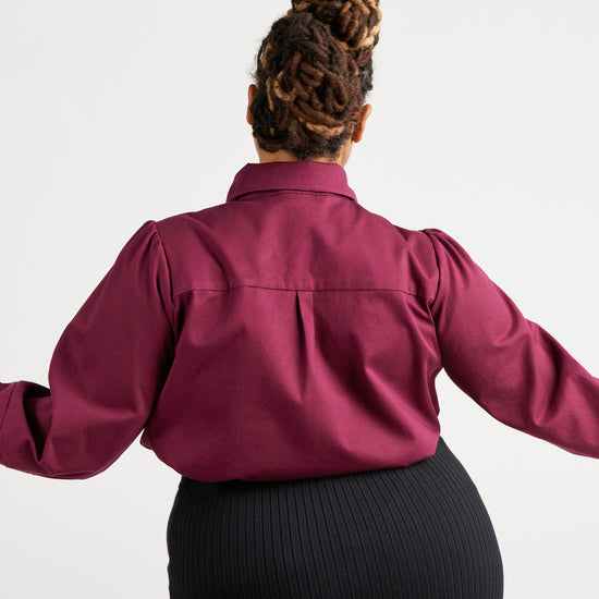 Person wearing a burgundy shirt with long sleeves on a white background. This top is the Vernon Shirt sewing pattern from Cashmerette.