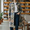 Woman in a patterned coat standing in a modern cafe with bookshelves in the background